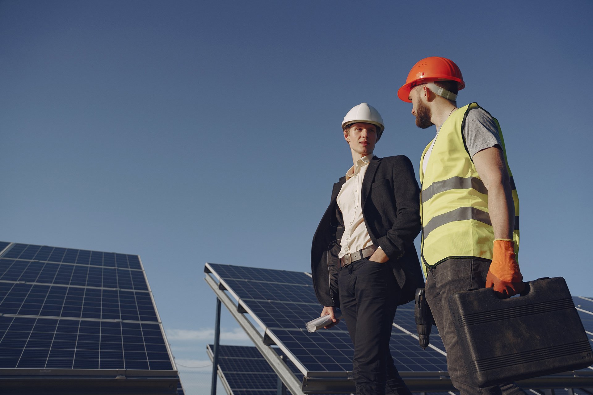 Businessman and worker near solar energy batteries. Business client showing photovoltaic detail to foreman. Two men making deal.